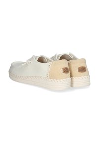 Chaussures slip-on en toile beige clair avec une semelle en jute tissée et un patch de talon en tissu beige contrastant. Détail en dentelle à l'avant pour un ajustement sécurisé.