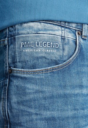 Džínové kalhoty s světle modrým odstínem, s vyšitým názvem značky "PME Legend" a "American Classic" v bílé barvě na zadní kapse.