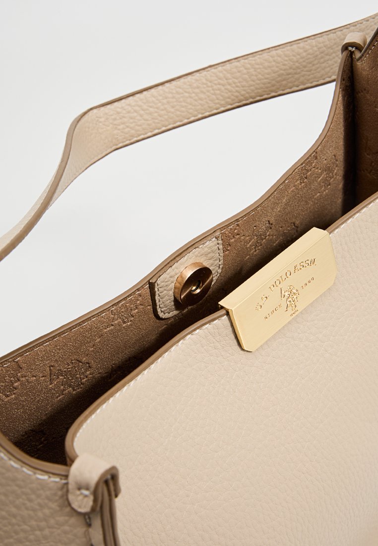 Borsa a tracolla in pelle beige con una superficie testurizzata, accessori in oro e chiusura a patta. L'interno presenta un sottile motivo con logo.