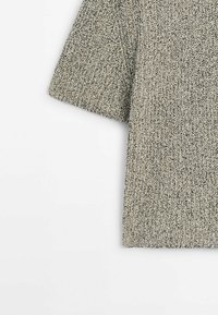 Pull à manches courtes en maille avec un motif côtelé texturé en fil beige tacheté et noir.