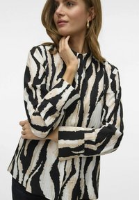 Lange mouwen blouse met een zwart en beige zebra-streeppatroon, met een kraag en knoopmanchetten. Gemaakt van gestructureerde stof.