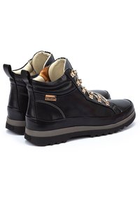Bottines en cuir noir avec une tige texturée, un col rembourré, des éléments en métal décoratifs et une semelle en caoutchouc robuste. Présente le logo de la marque.