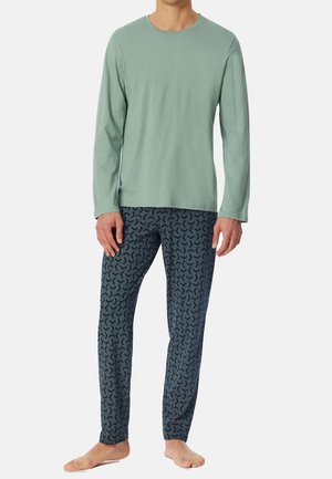 Camisa de manga larga verde claro combinada con pantalones de pijama azul oscuro que presentan un sutil patrón abstracto. Tejido suave con un corte relajado.