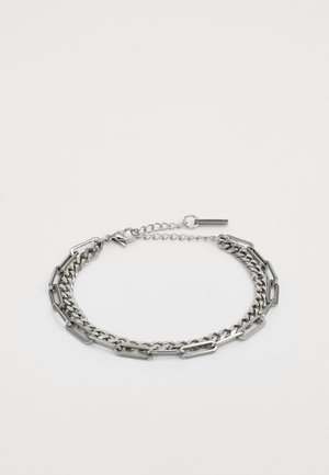 Bracelet en chaîne argentée à double couche avec un mélange de maillons rectangulaires et ovales, et un fermoir ajustable sur fond blanc.