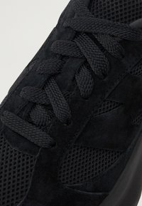 Pantof black de sport cu parte superioară din suede, panouri din plasă și șireturi groase. Dispune de o suprafață texturată și o talpă rotundă din cauciuc.