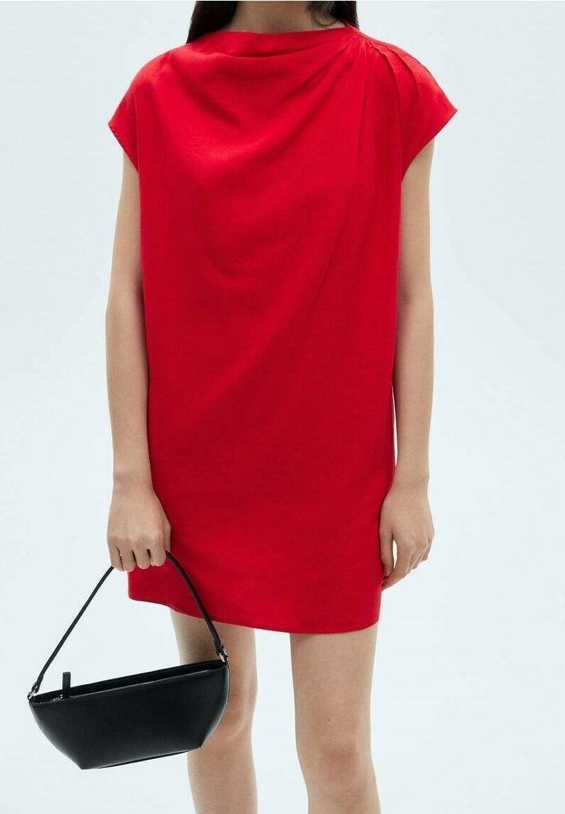 Rotes Kleid mit kurzen Ärmeln und lockerem Sitz, mit einem drapierten Ausschnitt. Modell hält eine kleine schwarze Tasche mit geschwungener Form und Tragegurt.