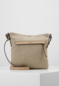 Beige axelväska i canvas med läderrem, försedd med dragkedja upptill och en fram panel i läder med präglad logotyp.