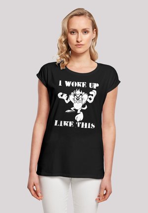 Schwarzes T-Shirt mit kurzen Ärmeln und rundem Ausschnitt, ausgestattet mit einer weißen Grafik eines Cartoon-Charakters und dem Text "ICH BIN SO AUFGEWACHT."