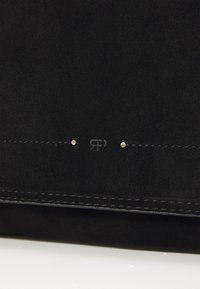 Svart mockaskinns plånbok med en subtil präglad logotyp, gyllene nitar som accent och kontrasterande sömmar längs kanterna för extra detalj.