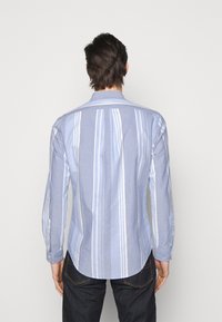 Ljusblå randig skjorta av mjukt tyg, med vita vertikala ränder, långa ärmar, klassisk krage och knappmanschetter.