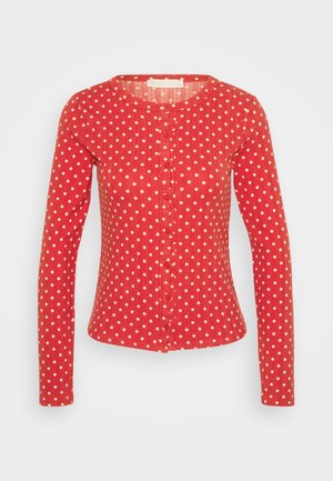 Chemise rouge à manches longues avec des pois blancs, encolure ronde et fermeture à boutons sur toute la longueur. Tissu léger avec une finition légèrement texturée.