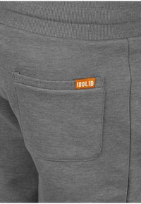 Gray sweatpants featuring a back pocket with an orange "ISOLID" logo, ribbed waistband, and soft cotton texture.