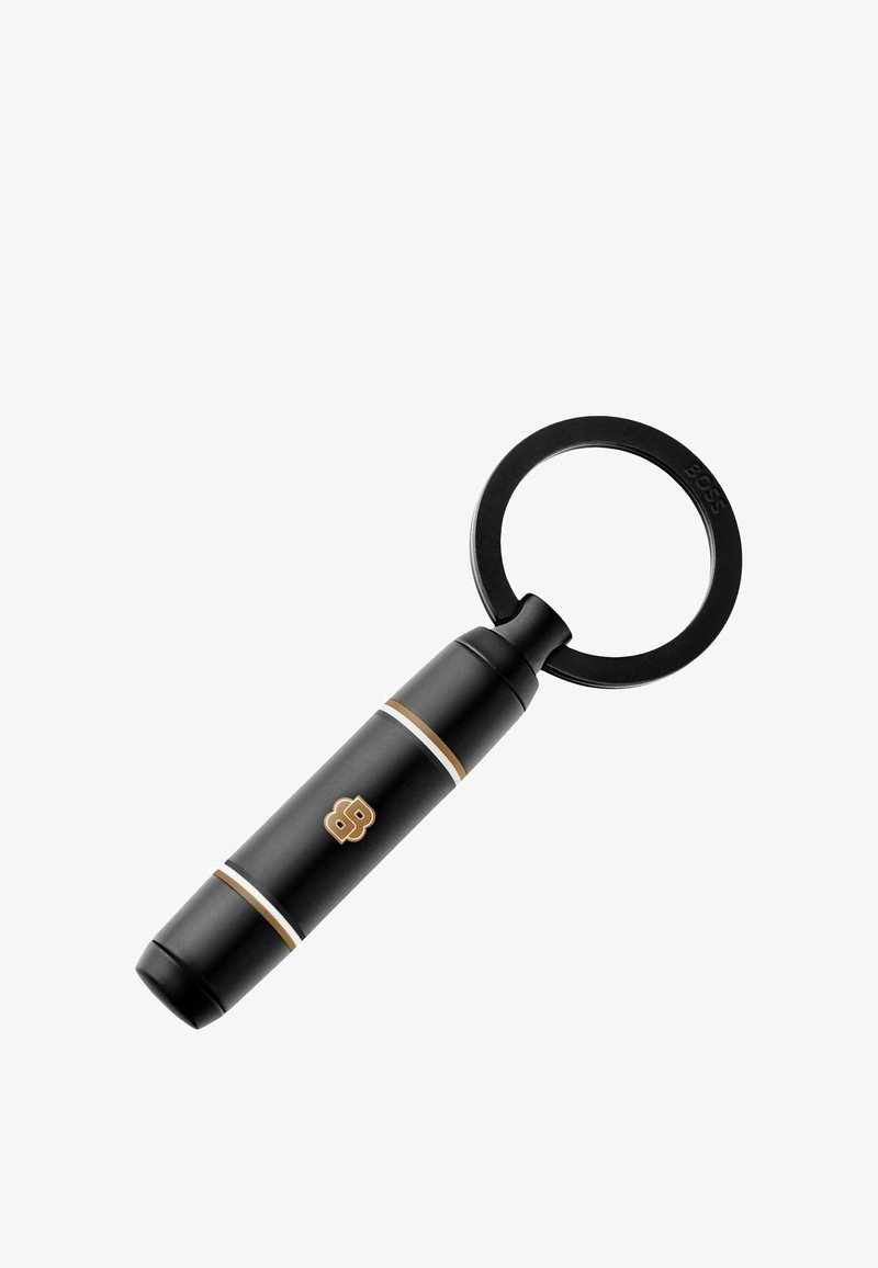 Črna cilindrična obesek za ključe z zlato-belimi črtami, zlatim logotipom "BB" in okroglo črno obročem, pritrjenim na enem koncu.
