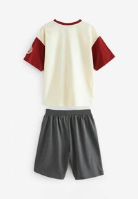 Kortärmad krämfärgad T-shirt med vinröda accenter och logotyp, tillsammans med grå shorts med elastisk midja. Material i bomullsblandning, avslappnad design.