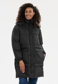 Svart puffig jacka med hög krage, två framfickor och elastiska ärmslut. Materialet är glänsande med en quiltad textur.