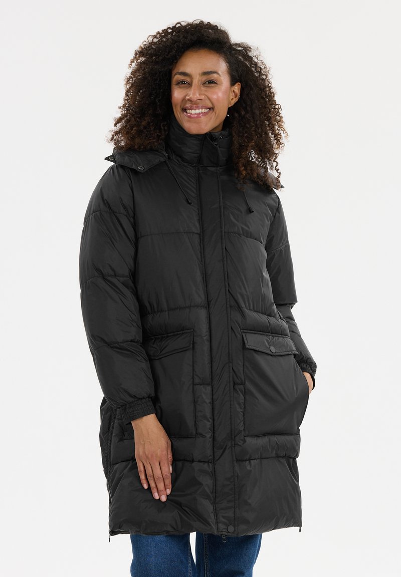 Svart puffig jacka med hög krage, två framfickor och elastiska ärmslut. Materialet är glänsande med en quiltad textur.