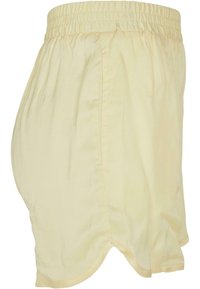 Pantaloni corti gialli in cotone con vita elasticizzata, caratterizzati da una vestibilità ampia e un orlo curvo. Texture liscia con tasche laterali.