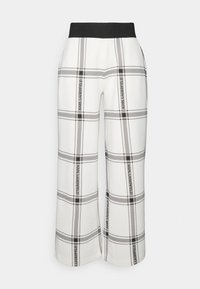 Białe spodnie w kratę z czarnymi liniami, o szerokich nogawkach. Posiadają elastyczny czarny pas oraz miękką fakturę, zapewniającą luźne dopasowanie.
