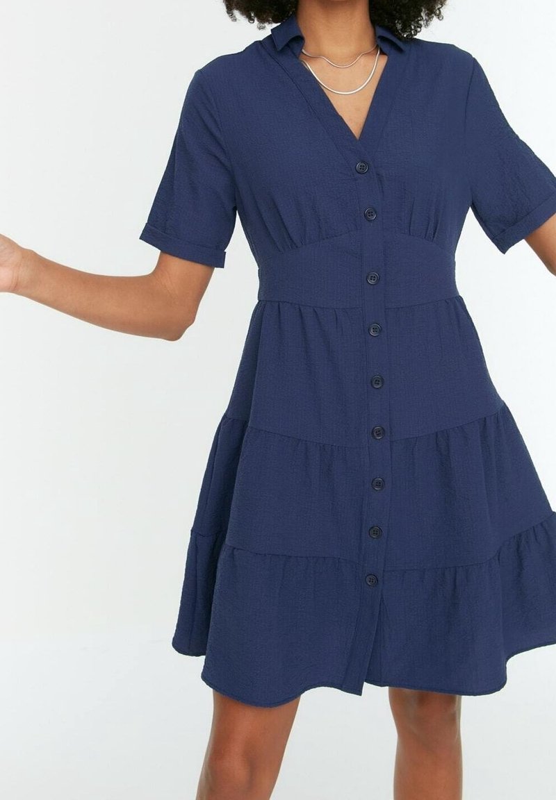 Abito camicia blu navy con maniche corte, chiusura a bottoni, design a strati, tessuto testurizzato e orlo curvo.