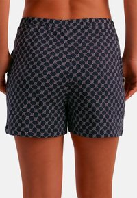 Pantalones cortos de color azul marino con un patrón geométrico blanco, cintura elástica y aberturas laterales. Hechos de tejido suave que ofrece un ajuste relajado.