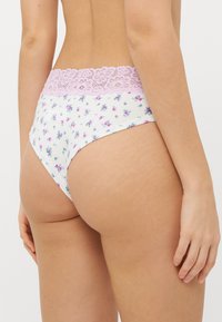 Blaue Unterwäsche mit floralem Muster und einem rosa Spitzenbund. Der Stoff ist weich und zeigt kleine lila und rosa Blumen, die gleichmäßig verteilt sind.