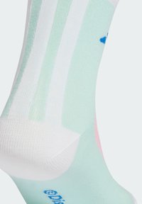Calzini alla caviglia di un verde chiaro e bianco con strisce orizzontali, caratterizzati da un motivo a maglia testurizzato e un piccolo logo blu vicino al tallone.