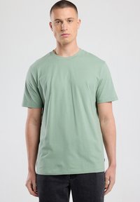 Light green short-sleeve T-shirt in soft, breathable fabric. Features a round neckline and relaxed fit with no visible patterns or graphics.