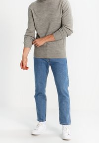 Harmaa neulepaita pitkähihainen, yhdistetty vaaleansinisiin slim fit -farkkuihin ja valkoisiin tennareihin. Yksinkertainen muotoilu ilman näkyviä kuvioita.