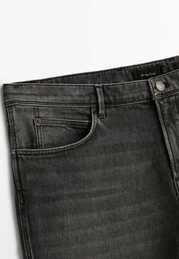 Mörkgrå denimjeans med framfickor, bältesöljer och knäppning med metallknapp på vit bakgrund.