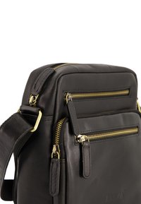 Sort læder crossbody taske med gyldne lynlåse, flere rum og en aftagelig rem med hardware detaljer. Struktureret overflade.