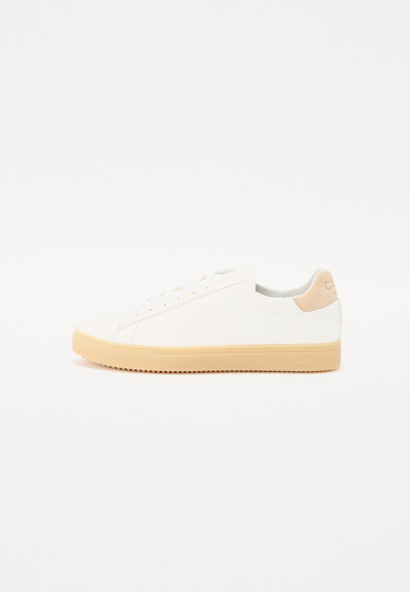 White sneakers made of smooth leather with a beige suede heel accent and a light tan rubber sole, featuring classic lace-up design.