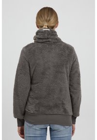 Grå, fluffig fleece-pullover med hög krage, ribbad nederkant och ärmslut. Mjuk textur med avslappnad passform och inga synliga mönster eller detaljer.