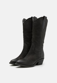 Bottes de cowboy en suède noir avec un bout pointu et un petit talon empilé. Comprend des languettes de tirage et un design cousu sur l'empeigne.