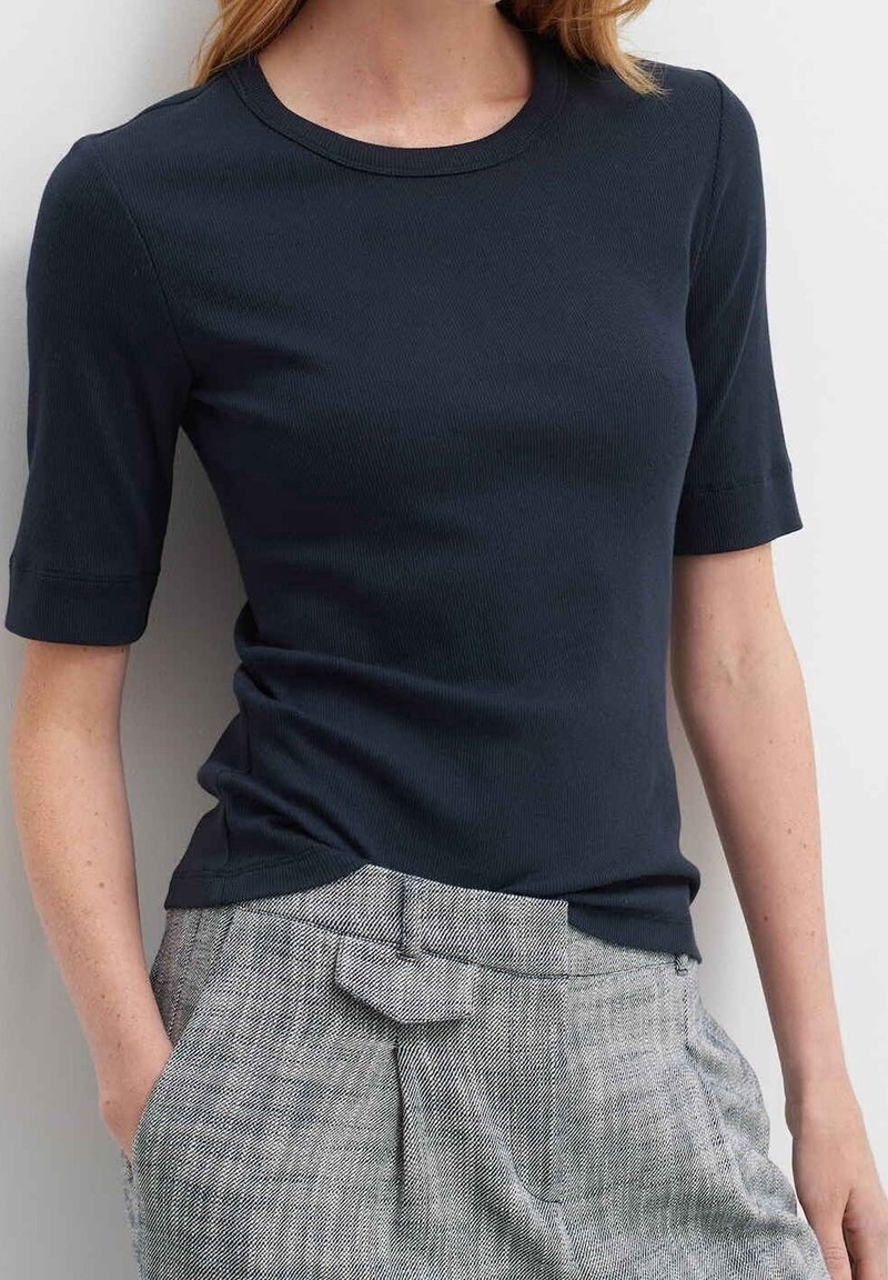 Marineblå ribbet kortærmet t-shirt med rund halsudskæring, parret med tekstureret grå højtaljet bukser med en sløjfeaccent i taljen.