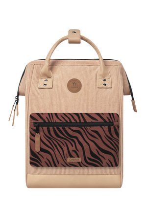 Beiger Cord-Rucksack mit hellbraunen Griffen und vorne einer schwarzen und braunen zebragestreiften Reißverschlusstasche, mit dem Label Cabaia.