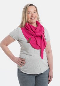 Roze gebreide sjaal met een structuurpatroon, voorzien van een houten labelaccent en nonchalant om de nek gedrapeerd, gecombineerd met een grijs shirt.