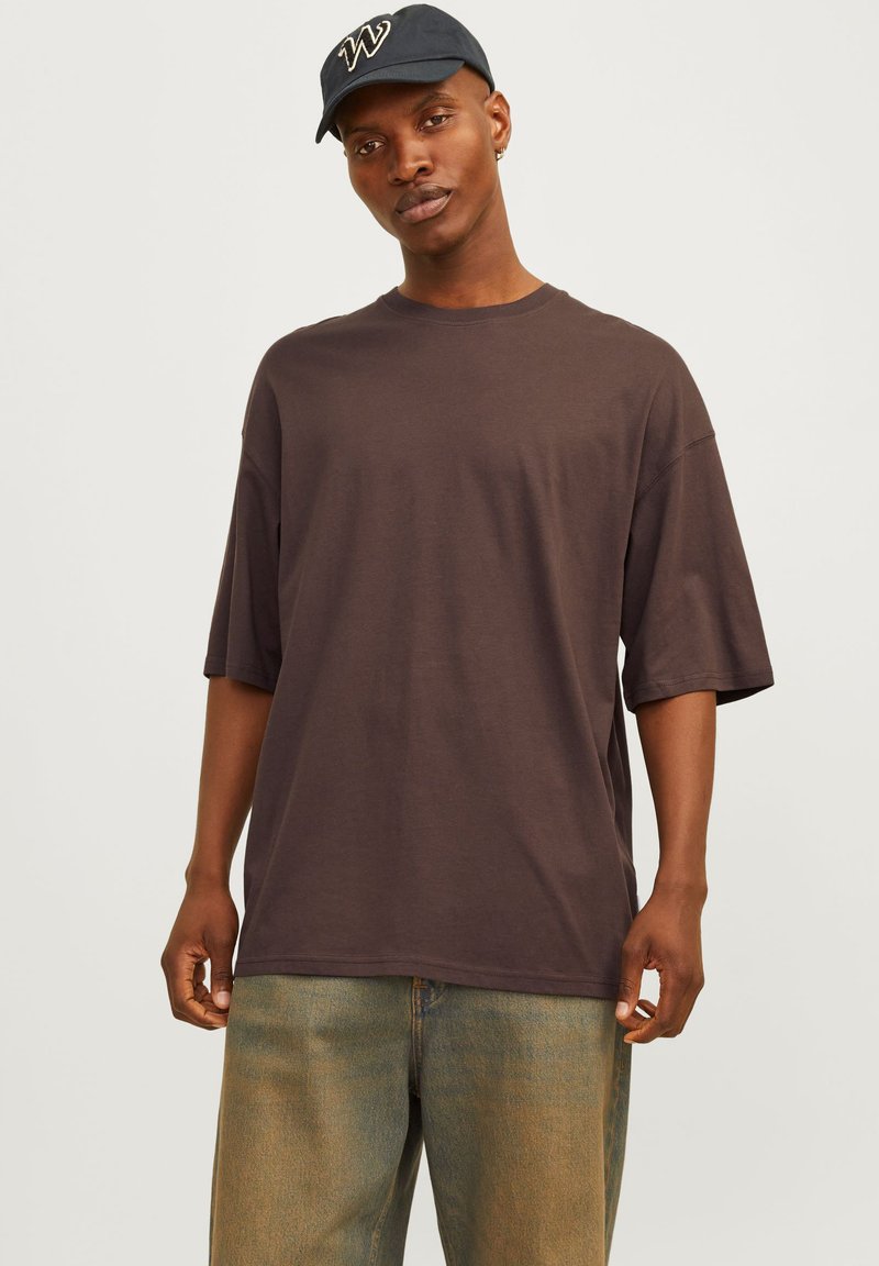 Mørkebrun kortærmet t-shirt lavet af bomuld. Rund halsudskæring, afslappet pasform, parret med lyseblå vide jeans. Enkel design, ingen mønstre.