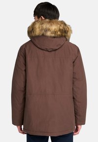 Brun isolerad parkajacka med stor fuskpälskrage, utrustad med huva och rak skärning, lämplig för kallt väder.