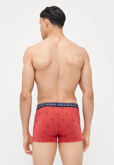 Rdeče bokserice z modrim pasom, na katerem so majhni logotipi Polo Ralph Lauren. Gladka tekstura in prilegajoč dizajn, prikazano zadaj.