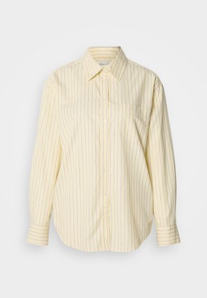 Cămașă cu dungi galbene și nasturi, mâneci lungi, guler clasic și un buzunar simplu la piept. Dungi albastre pe un material moale, texturat.