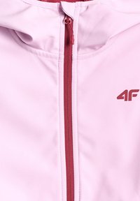 Veste rose avec fermeture éclair rouge et logo "4F" sur la poitrine droite, montrant le col et la partie supérieure avant.