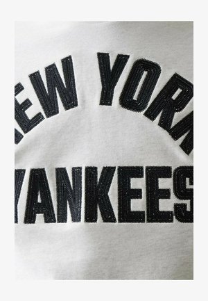Schwarzer, bestickter Text "NEW YORK YANKEES" auf weißem Stoffhintergrund, zentriert und in einem Bogen- sowie geraden Linien-Design angeordnet.