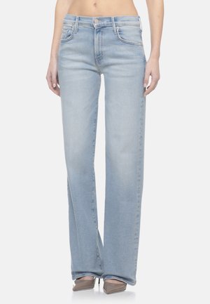 Donna che indossa jeans a vita alta di colore azzurro chiaro con gambe dritte, abbinati a tacchi beige con punta appuntita, tagliati in vita e alle caviglie.
