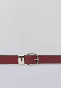 Rode leren riem met zilverkleurige hardware. Voorzien van een ronde gesp en een subtiel geperst logo op de metalen sluiting. Gladde textuur.