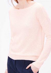 Maglione rosa chiaro lavorato a maglia con scollo ampio, maniche lunghe e polsini a costine. Tessuto testurizzato con un motivo sottile. Vestibilità casual.
