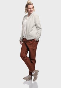 Light gray padded bomber jacket, brown cargo pants, beige sneakers; smooth texture, zippered front, side pockets on pants, casual fit.