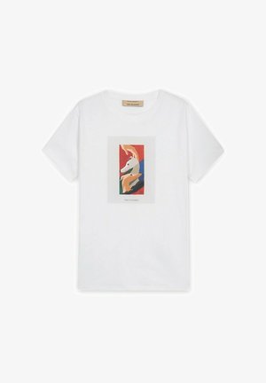 Hvid T-shirt med korte ærmer og farverigt abstrakt motiv af hundehoveder i røde, blå, grønne og beige nuancer placeret midt på forsiden.