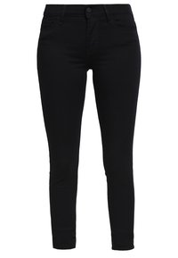 Pantalones vaqueros negros ajustados de denim. Presentan un diseño clásico de cinco bolsillos, cierre de botón y costuras minimalistas. Textura suave.