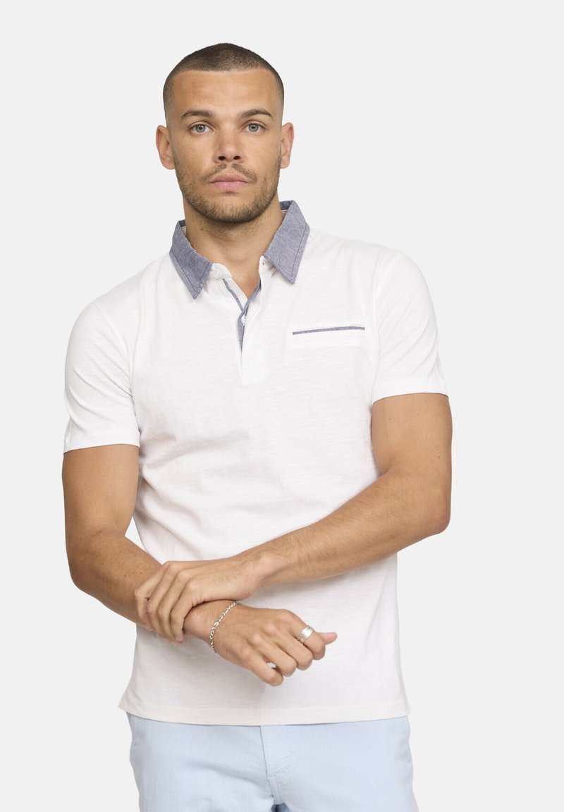 Polo shirt blanc à manches courtes avec un col en chambray texturé et une petite poche poitrine ornée d'une rayure horizontale.