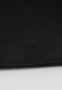 Borsa nera in pelle con texture, con logo "ESPRIT" impresso. Design elegante e minimalista, senza hardware o dettagli visibili.